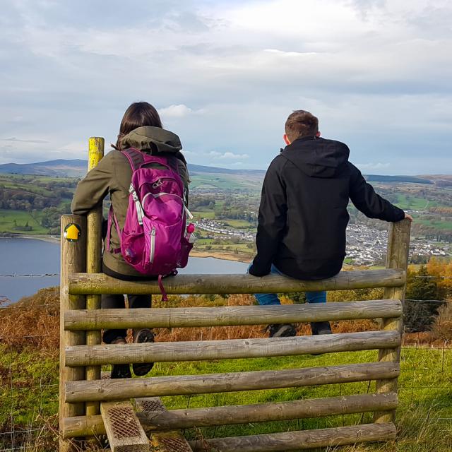 Two people sitting on gate looking over estuary in Wales