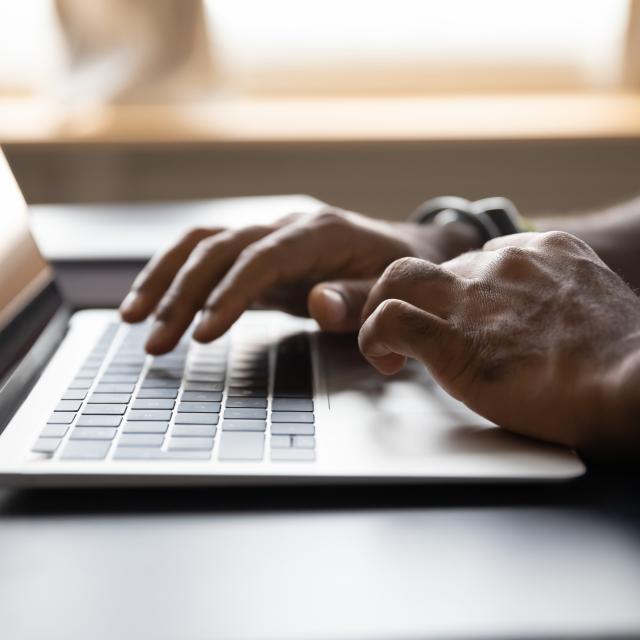 Image showing an identifiable person's hands typing on a laptop screen.