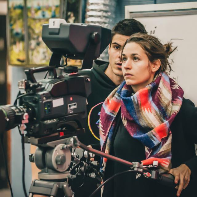 Cameraman and assistant shooting the film scene with camera in film studio