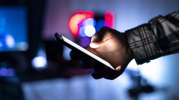 Person holding smartphone and scrolling on web page at night